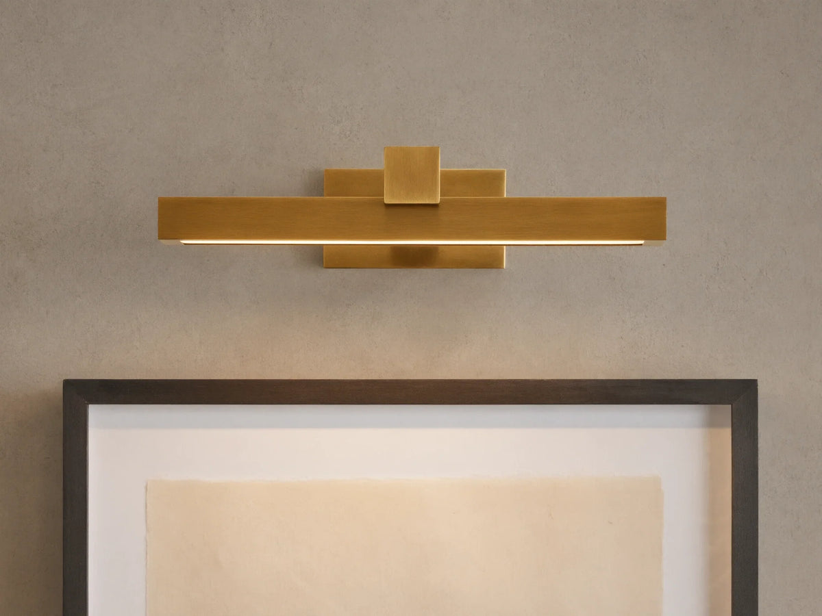 Corinth Picture Light Sconce, brass rectangular bar with LED light, mounted on wall above framed art.