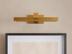 Corinth Picture Light Sconce, brass rectangular bar with LED light, mounted on wall above framed art.