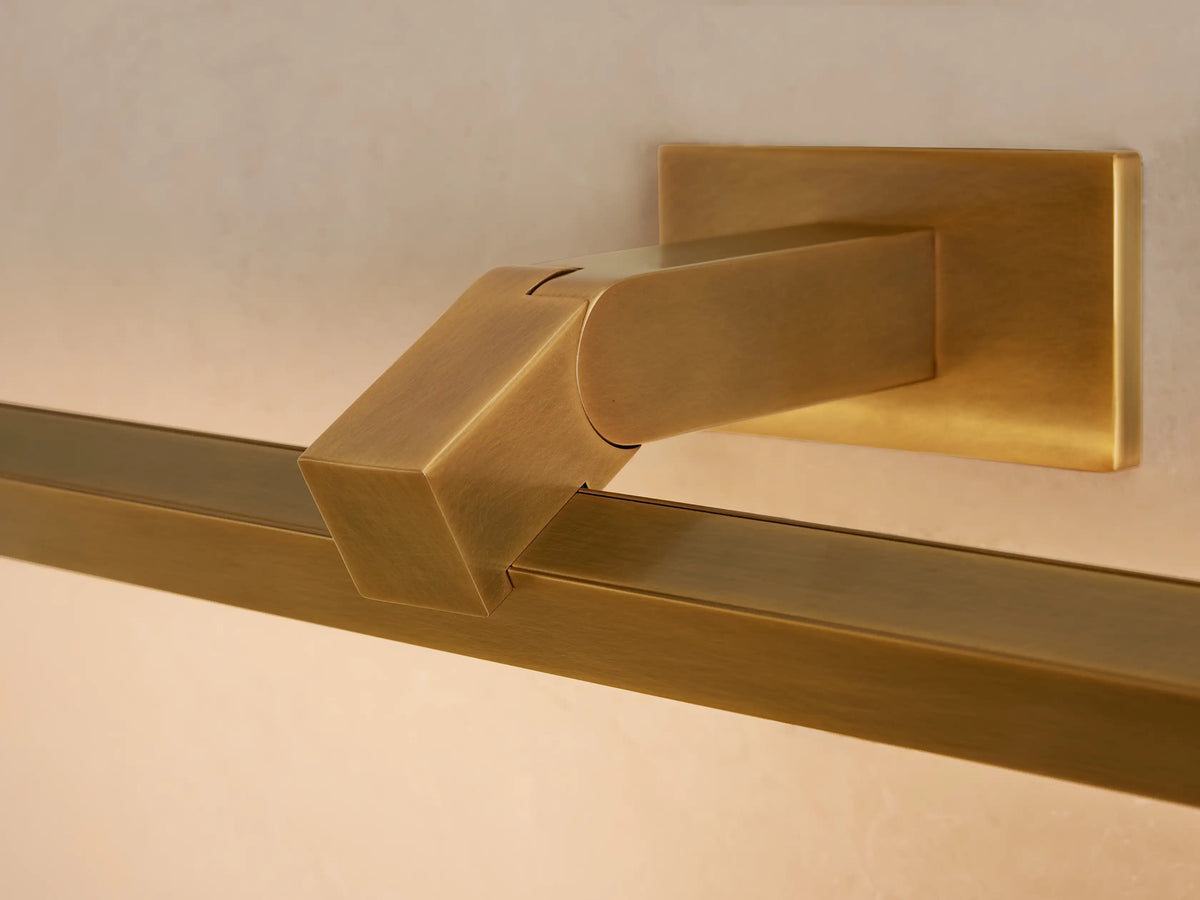 Corinth Picture Light Sconce, brass finish, mounted on a matching backplate above a framed artwork on a neutral wall.