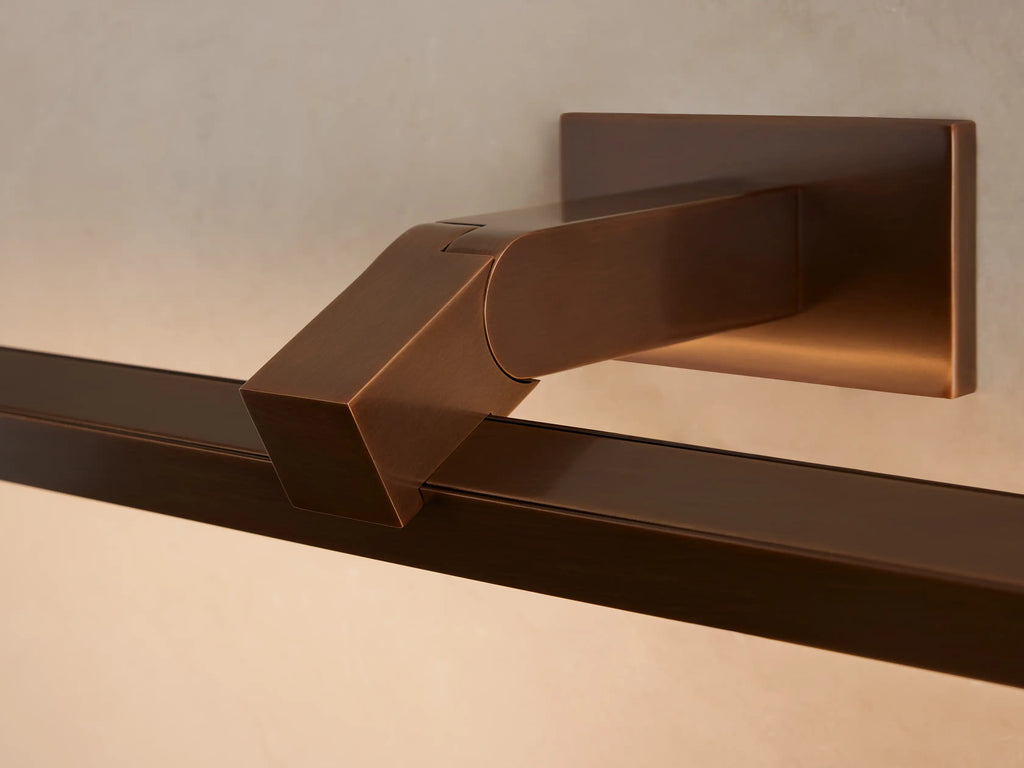 Bronze-finished Corinth Picture Light Sconce with rectangular bar & backplate, mounted on a beige wall above a framed art piece.