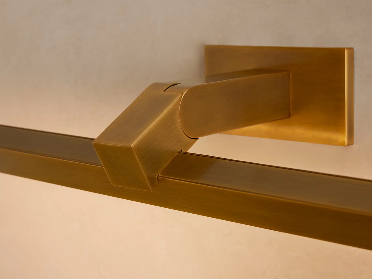 Brass Corinth Picture Light Sconce, horizontal, on a light wall above a framed abstract painting with a wood border.