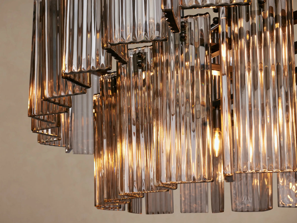 Delsie Oval Tiered Chandelier featuring two rows of smoky rectangular glass rods and a dark metal frame on a plain background.