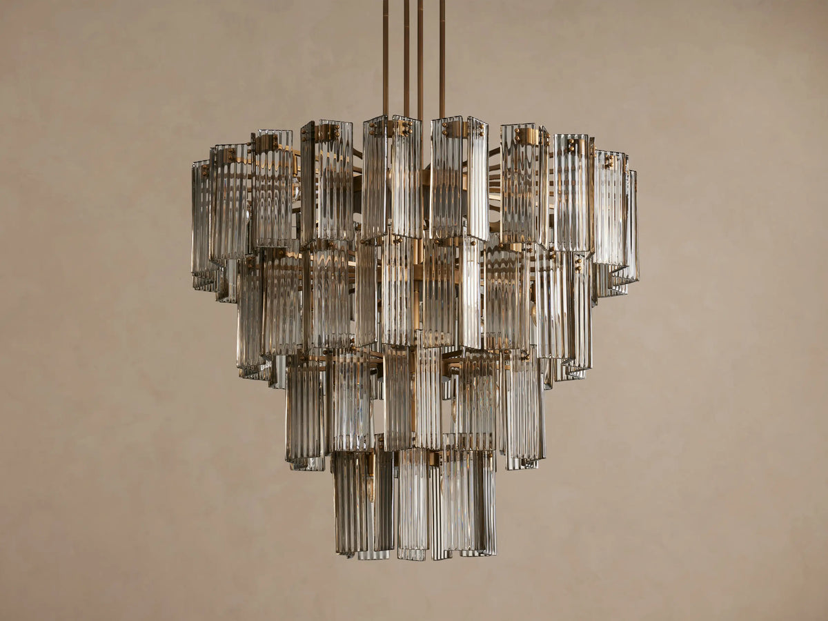 Delsie Round Chandelier, multi-tiered with clear fluted glass rods and burnished brass frame, glowing with warm light.