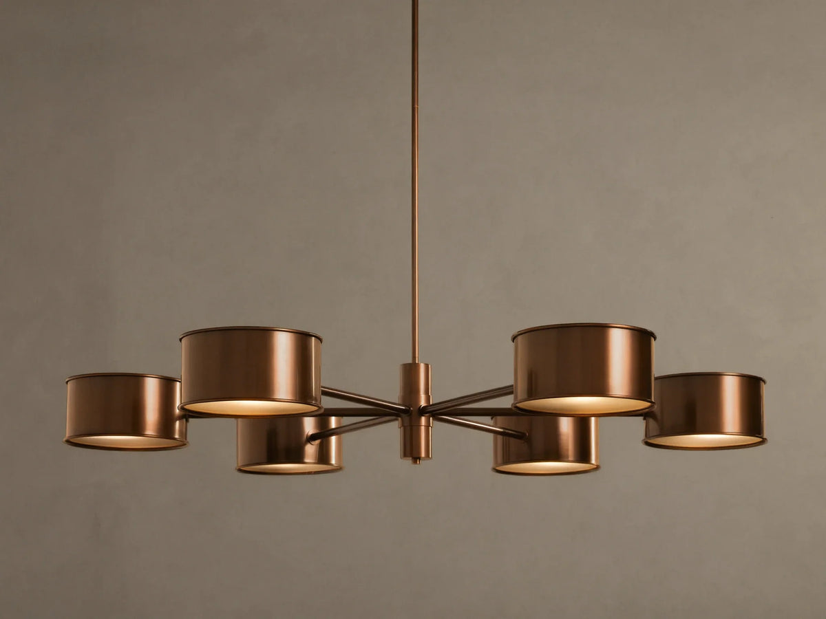 Daphne Metal Round Chandelier in warm bronze with six cylindrical shades, hanging from a rod, lights illuminated.
