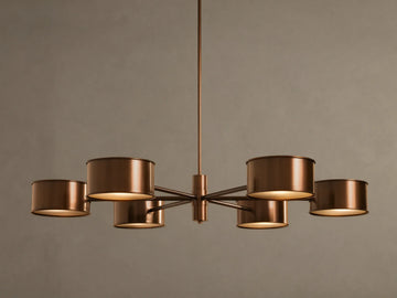 Daphne Metal Round Chandelier in warm bronze with six cylindrical shades, hanging from a rod, lights illuminated.