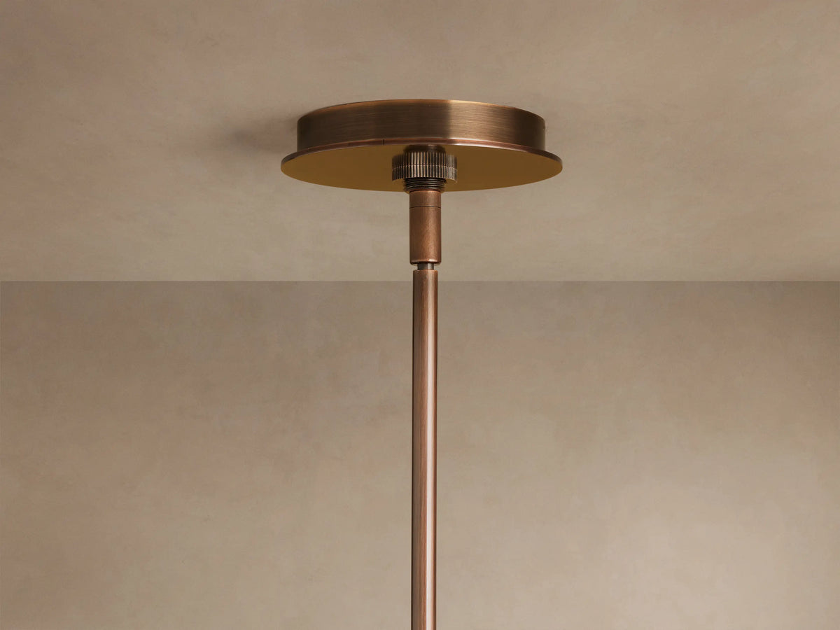 Close-up of Daphne Metal Round Chandelier with bronze finish. Two cylindrical shades illuminate warm light; a larger round shade glows above.