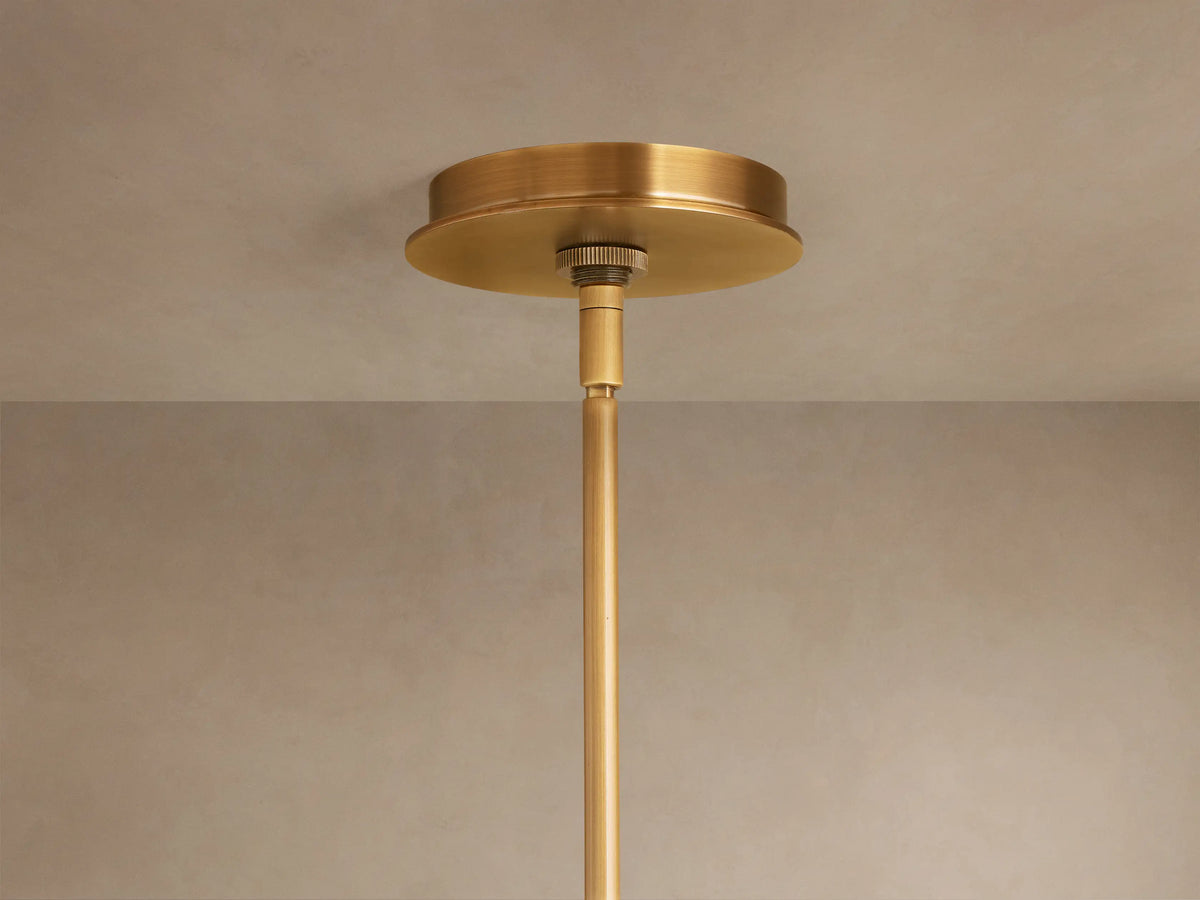 Daphne Metal Round Chandelier, antique brass finish. Close-up of several illuminated cylindrical shades emitting warm light.