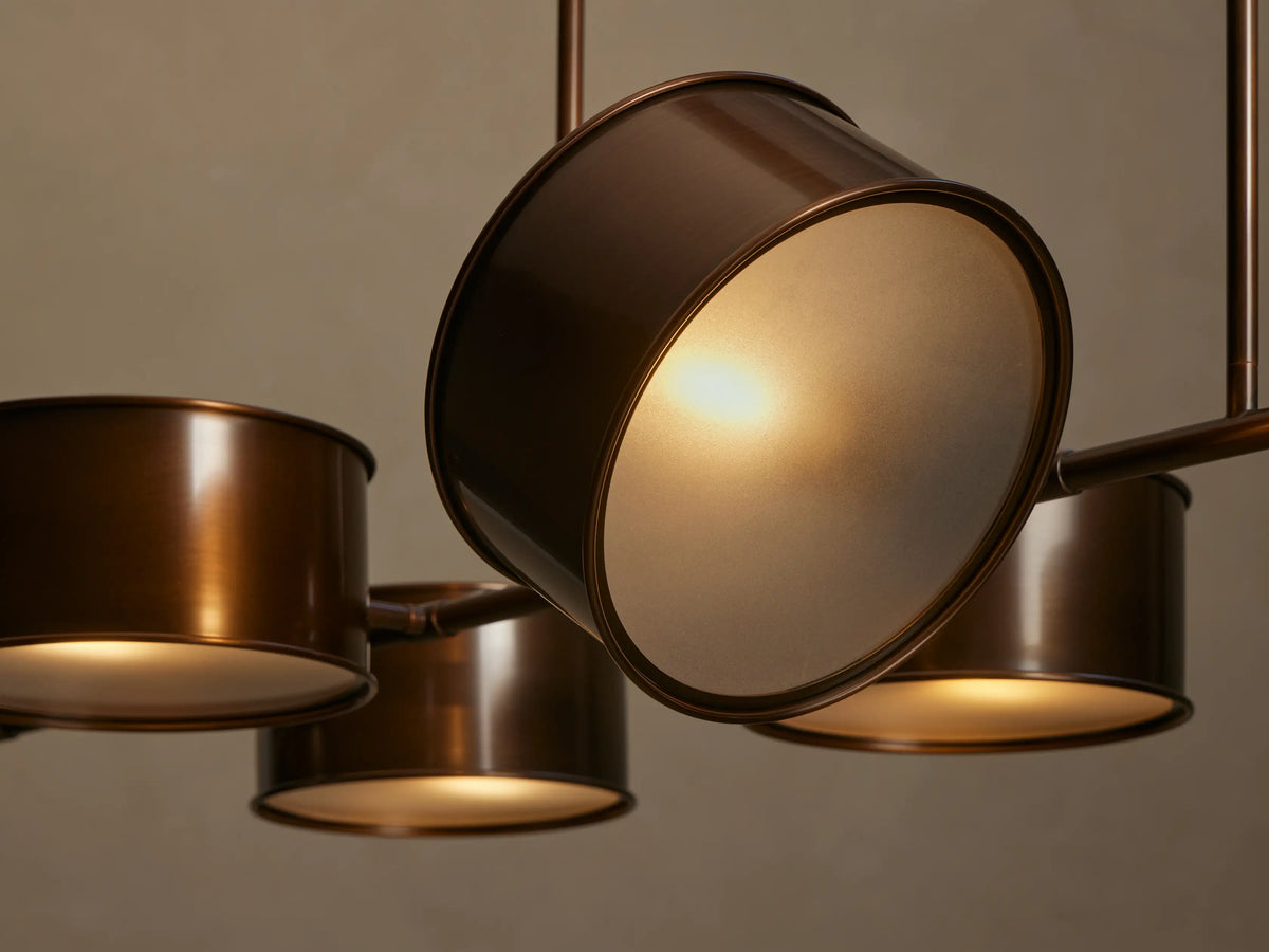 Daphne Metal Linear Chandelier, warm bronze with eight cylindrical shades arranged in pairs, hanging from two rods.