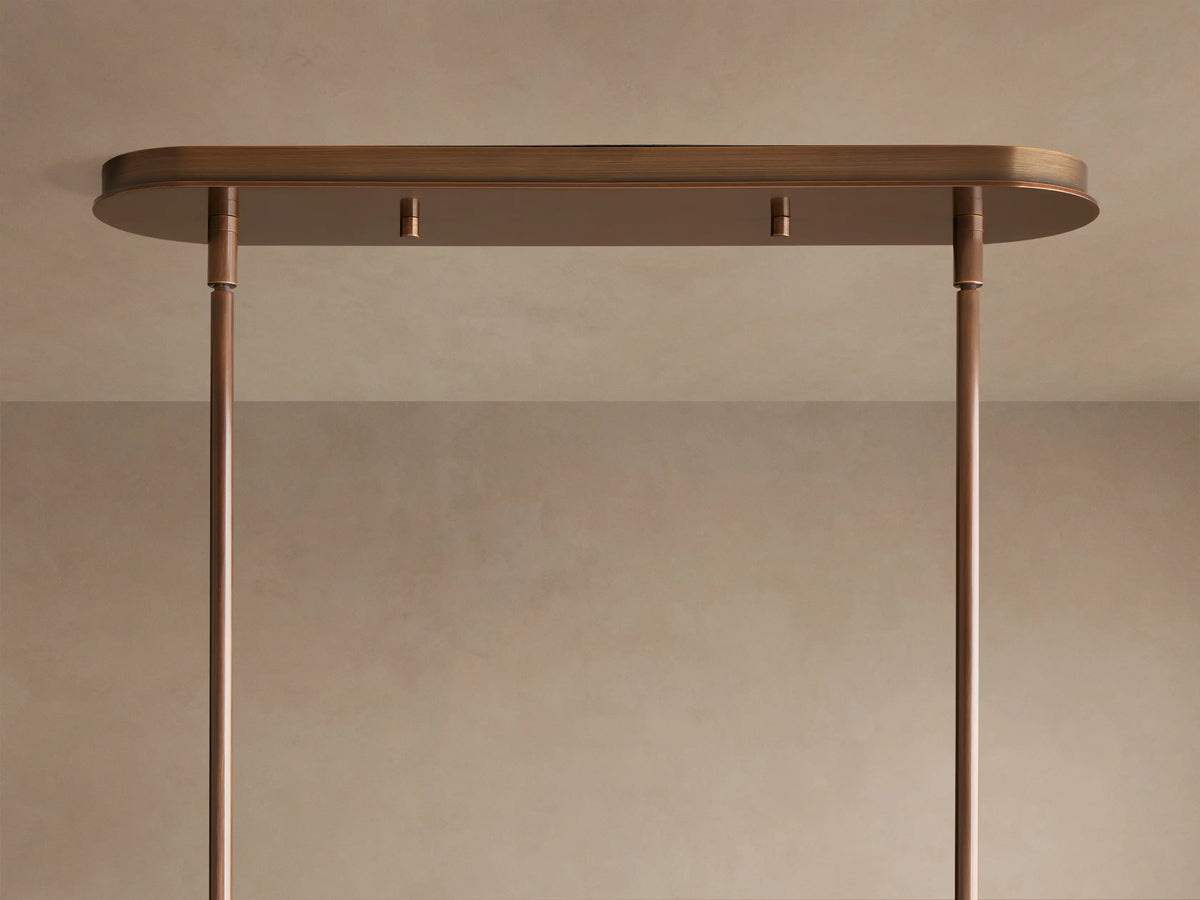 Close-up of Daphne Metal Linear Chandelier with multiple warm bronze metal shades glowing with soft, inviting light.