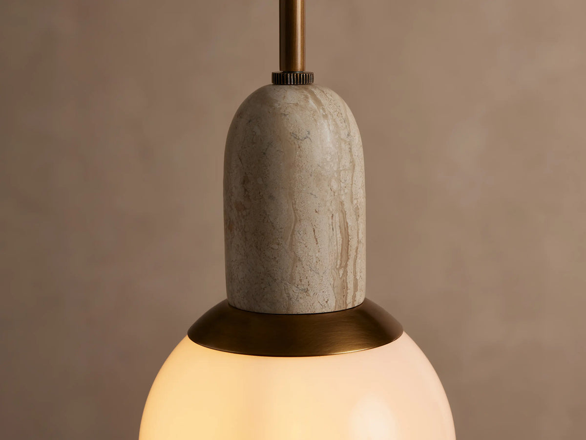 Christie Pendant hanging vertically. It features a brass rod, natural stone detail, brass ring, and spherical milk glass shade.