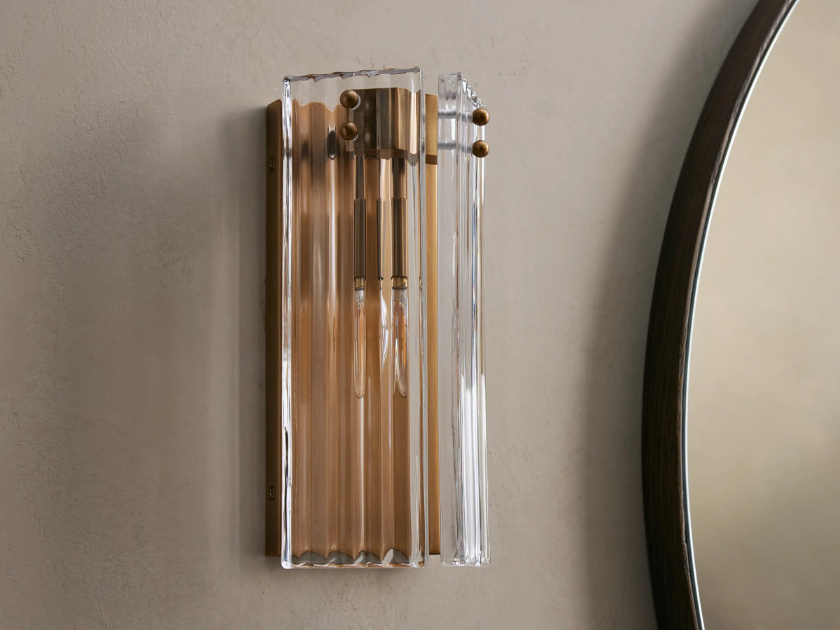 Delsie Sconce: Rectangular wall-mounted light with fluted clear glass and burnished brass frame, casting warm glow.