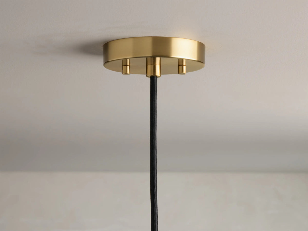 Close-up of a wavy, clear bubbled glass light shade with a warm glowing Edison bulb and a brass fixture.