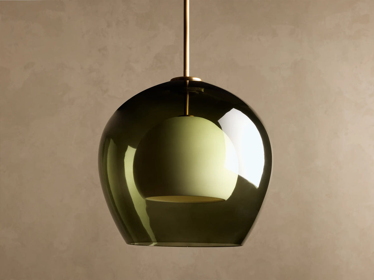 Romy Pendant featuring a dark green smoked glass outer dome and a light green inner shade, hanging from a brass rod.