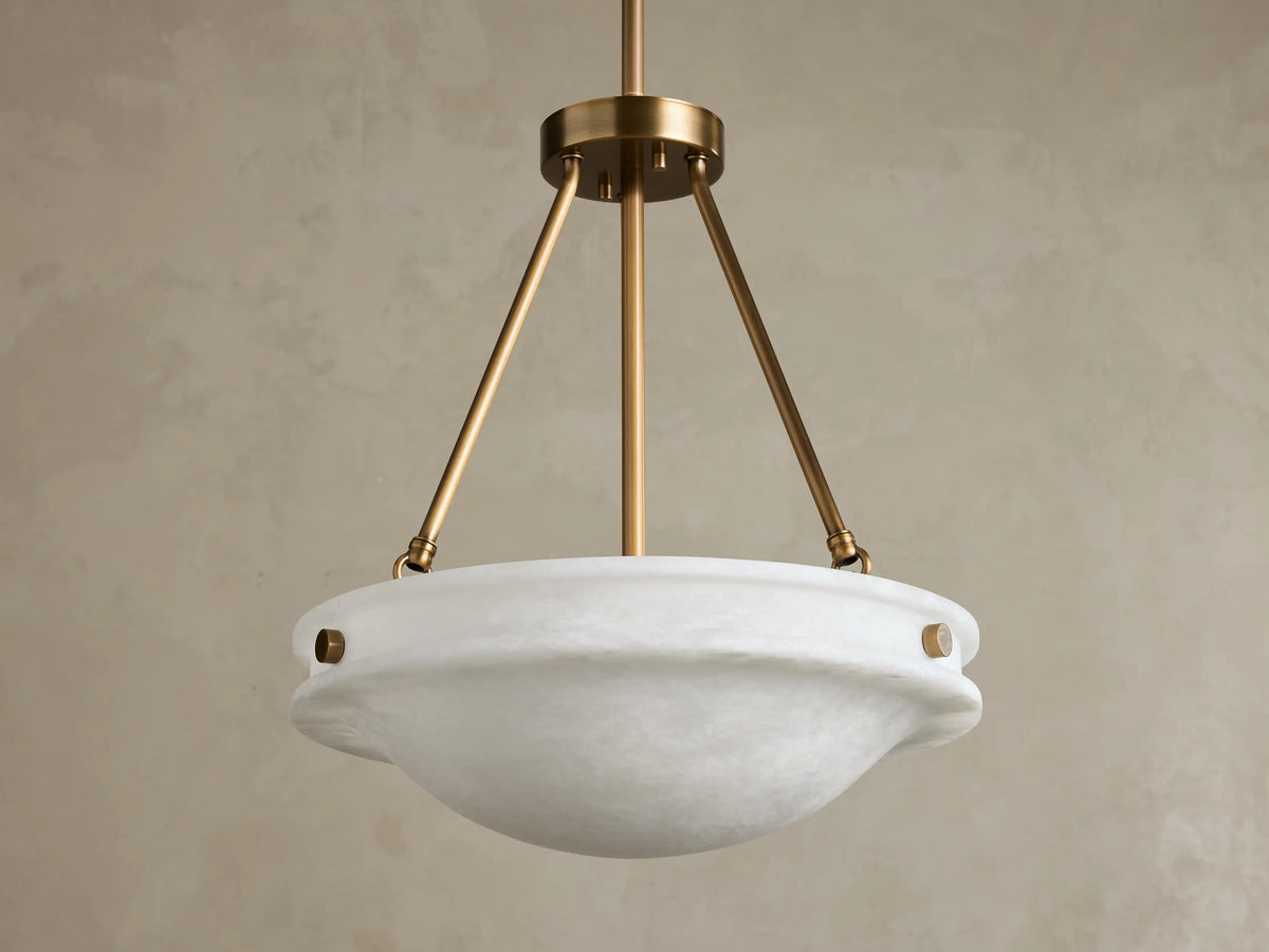 Front view of the Edith Pendant, featuring a white, subtly variegated alabaster stone bowl shade and a brass finish frame.