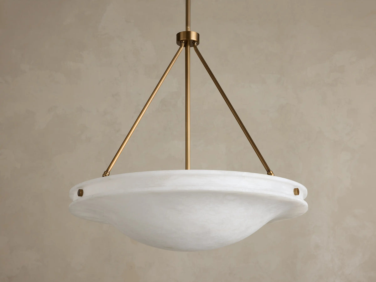 Front view of the Edith Pendant, a round white alabaster stone shade with subtle marbling, supported by three brass-finished rods.