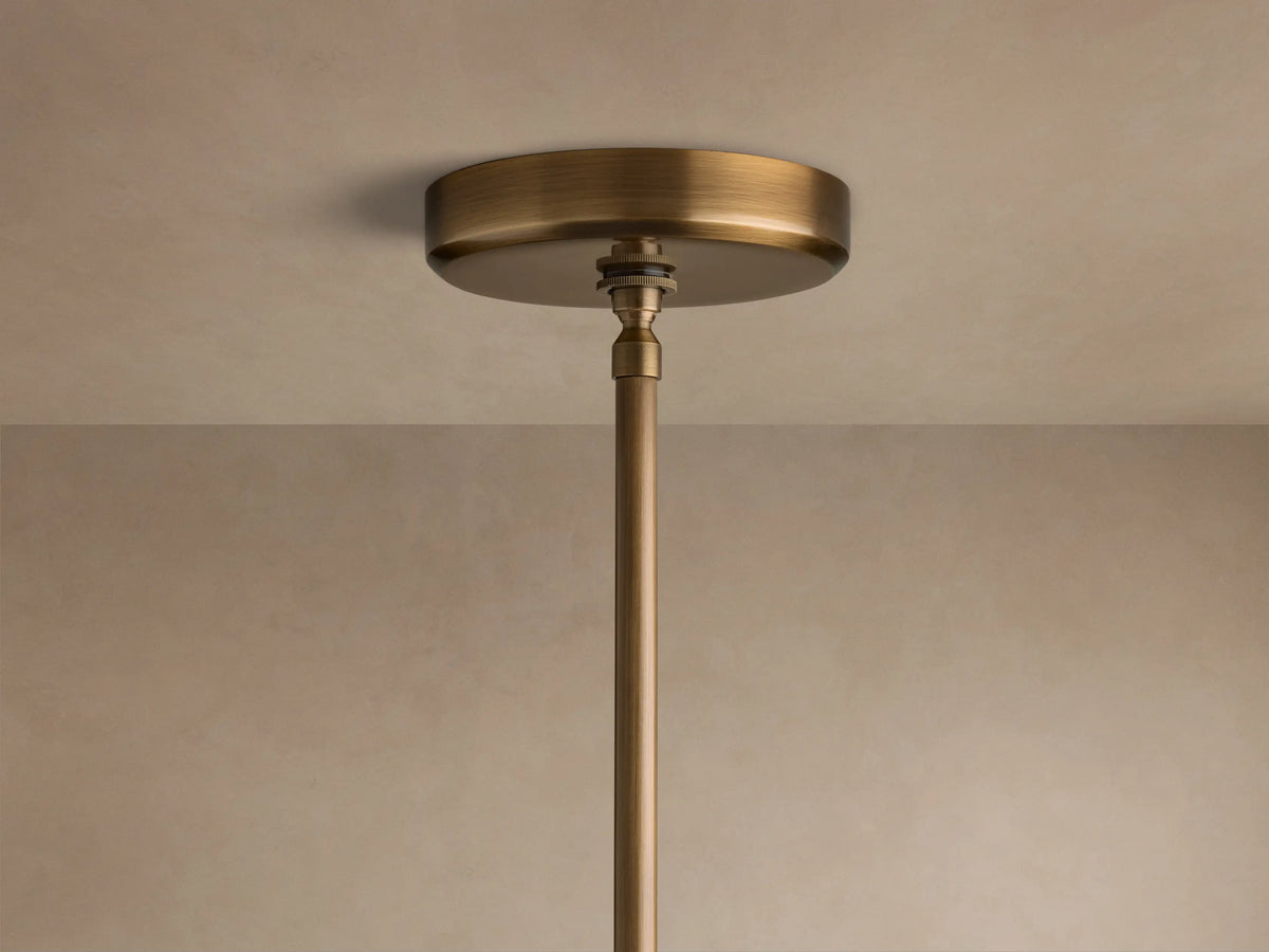 Close-up of the brass finish ceiling canopy and suspension rod of the Edith Pendant attached to a beige ceiling.