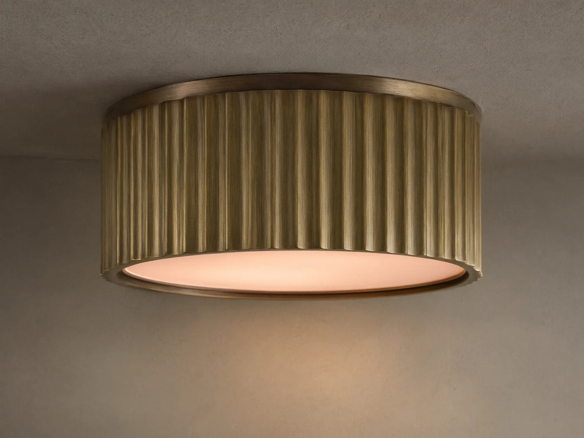 Upward view of a glowing brass ribbed flush mount ceiling light fixture against a white ceiling.