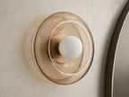 Front view of a wall sconce with a sculpted round amber glass shade, a brass-toned base, and a white globe bulb.
