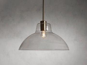 Bauer Dome Pendant with a clear glass dome and brass hardware, suspended from a rod and showing a visible bulb.