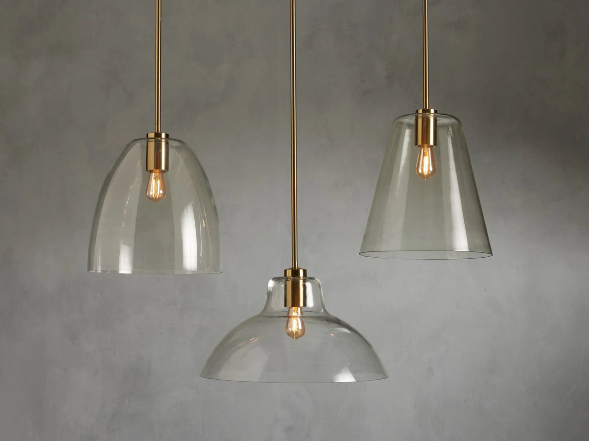 Bauer Dome Pendant features a brass-finished steel fixture with a clear glass dome, housing an LED bulb, against a neutral background.