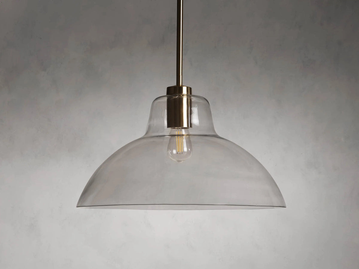 Bauer Dome Pendant with a clear glass dome and brass hardware, suspended from a rod and showing a visible bulb.