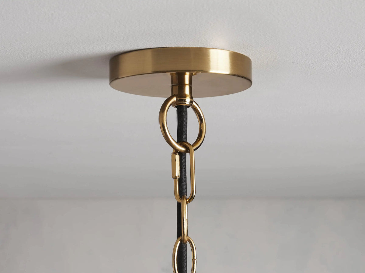 Bauer Dome Pendant with a clear glass dome shade and a brass-finished metal fixture, hanging from a brass rod against a neutral wall.
