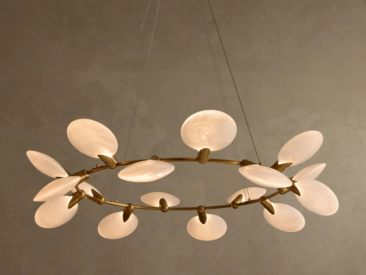 Warmly lit chandelier with a circular brass frame and multiple oval, translucent white diffusers with swirling patterns.