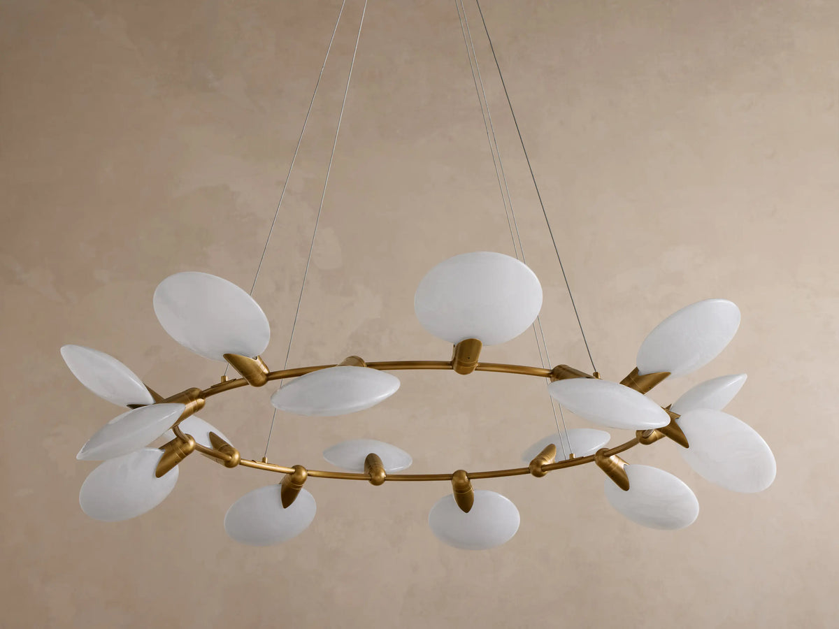 Close-up of a round, brushed gold light fixture canopy with white suspension cables hanging down from its underside.