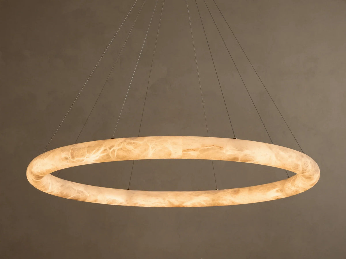 Front view of an illuminated Alabaster Ring Pendant Light, glowing warm white, revealing creamy translucent material with swirling veins.