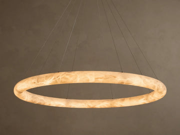 Front view of an illuminated Alabaster Ring Pendant Light, glowing warm white, revealing creamy translucent material with swirling veins.