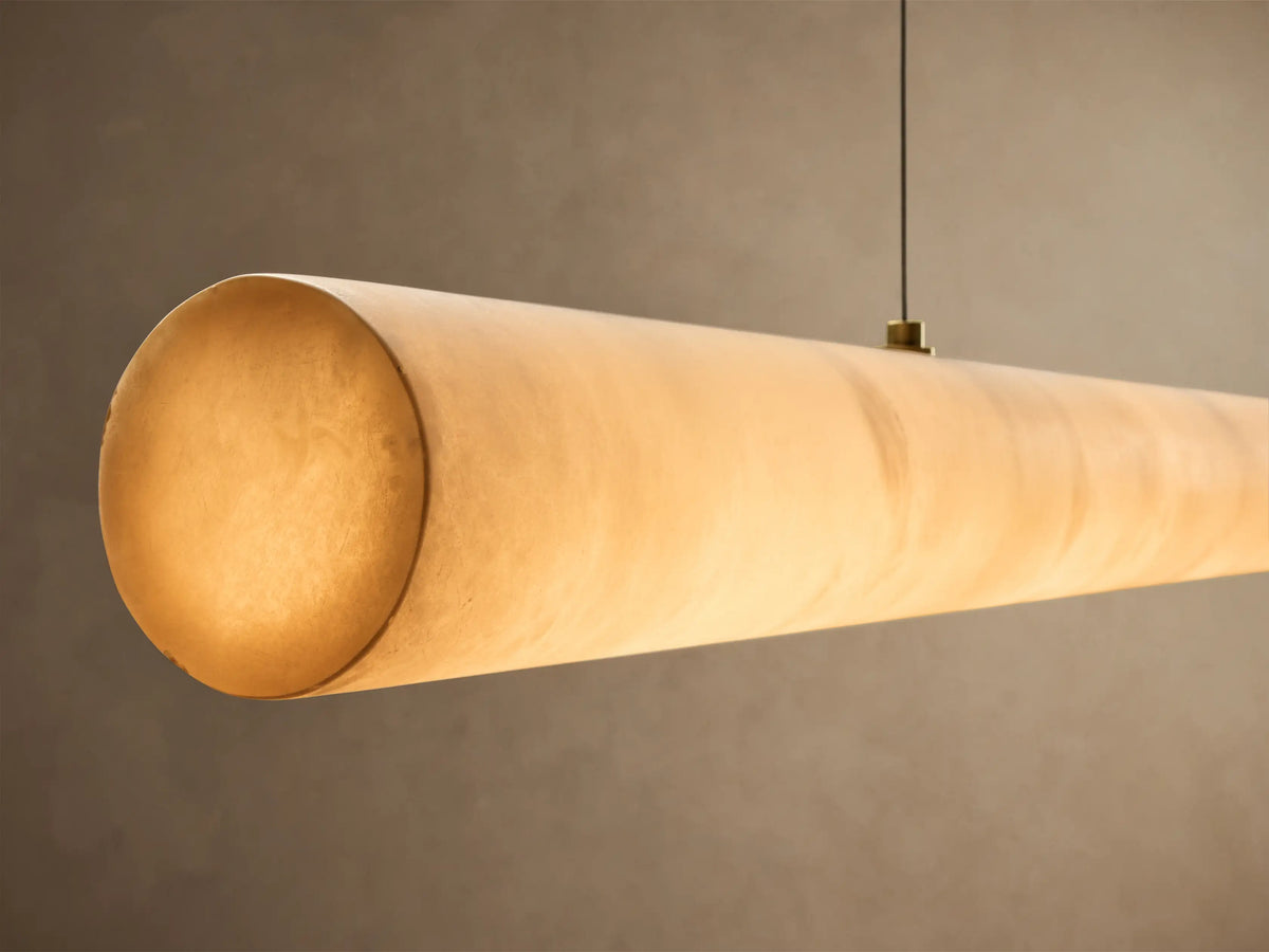 White marble cylindrical light fixture with pink veining, suspended horizontally by two wires.