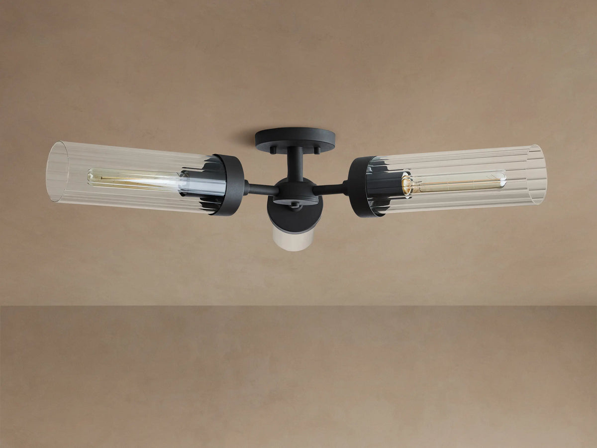 Andreas Flush Mount in dark bronze, with three clear fluted glass shades holding warm filament bulbs, mounted on a ceiling.