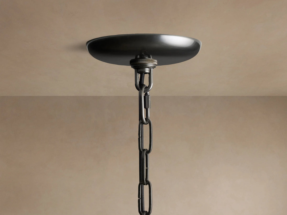 Close-up of the Ghiaccio Round Chandelier's dark metal canopy & chain, attached to a light beige ceiling.