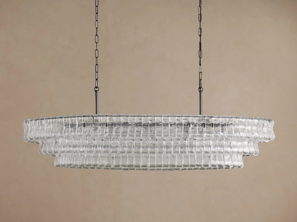 Front view of the Ghiaccio Oval Chandelier, featuring clear, curved tiered glass and dark metal chains. Bulbs glow softly.