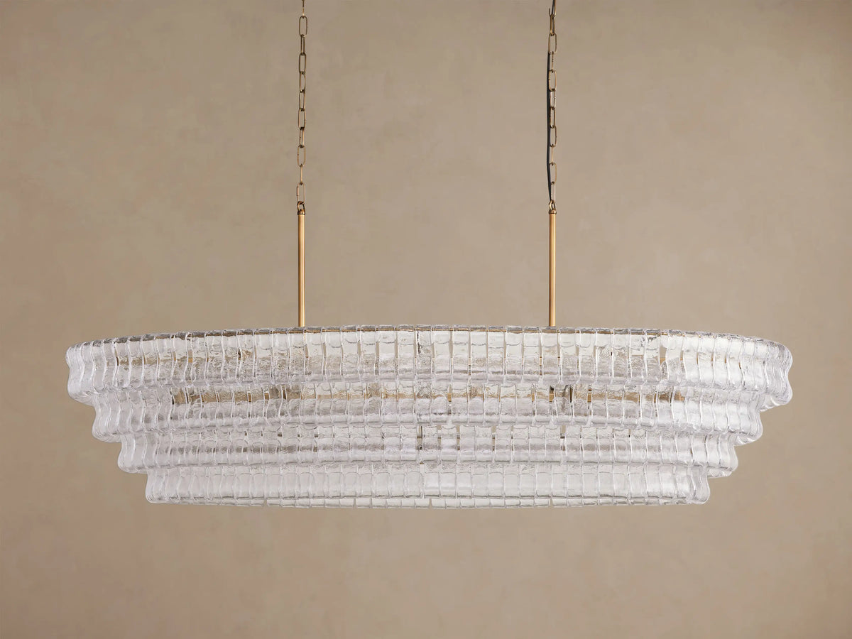 Oval Ghiaccio Chandelier with tiered, textured clear curved glass panels, glowing lights, suspended by gold rods & chains.