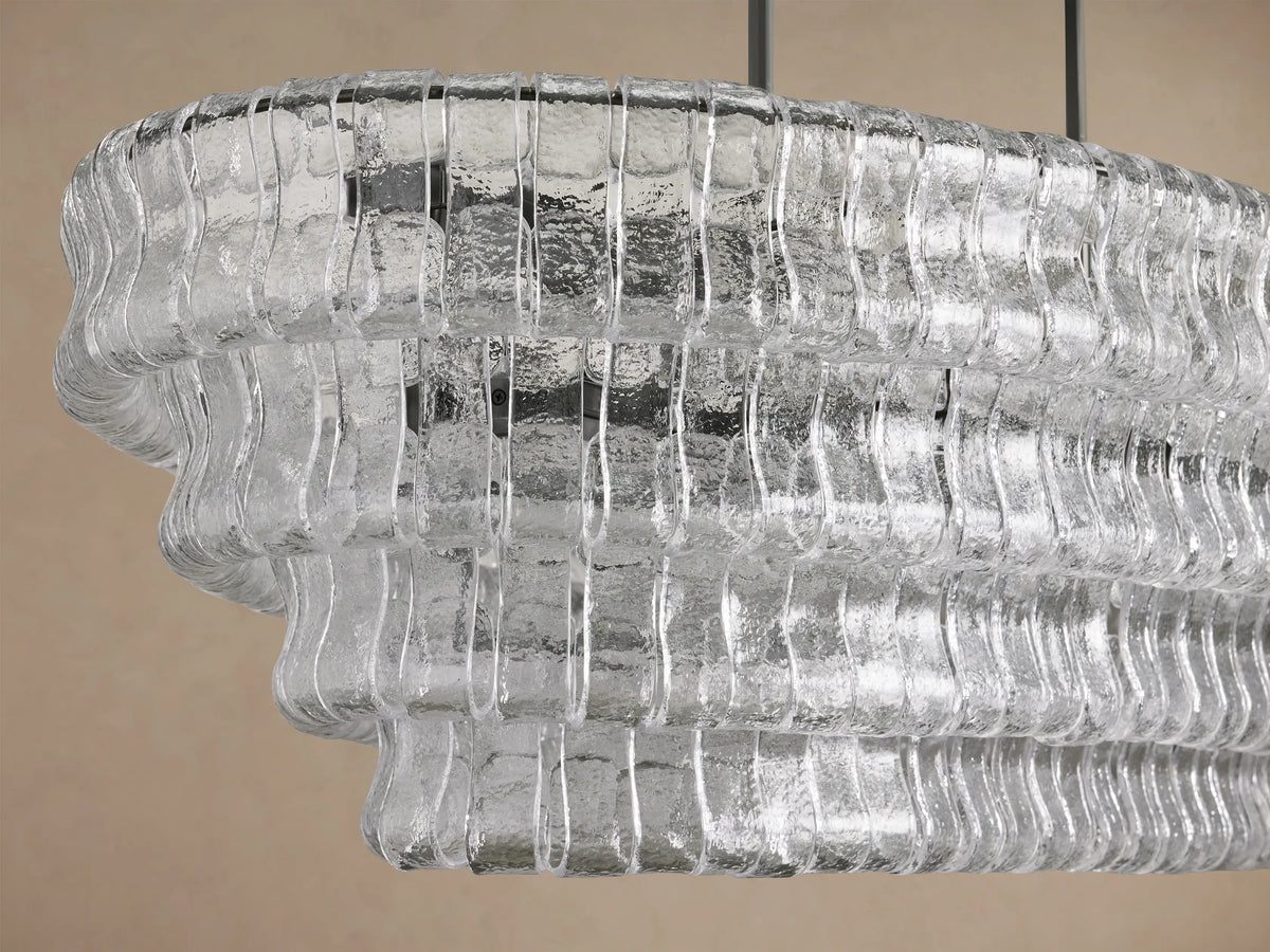 Ghiaccio Oval Chandelier, featuring clear, textured, curved glass in multiple tiered rows, suspended by dark metal chains.