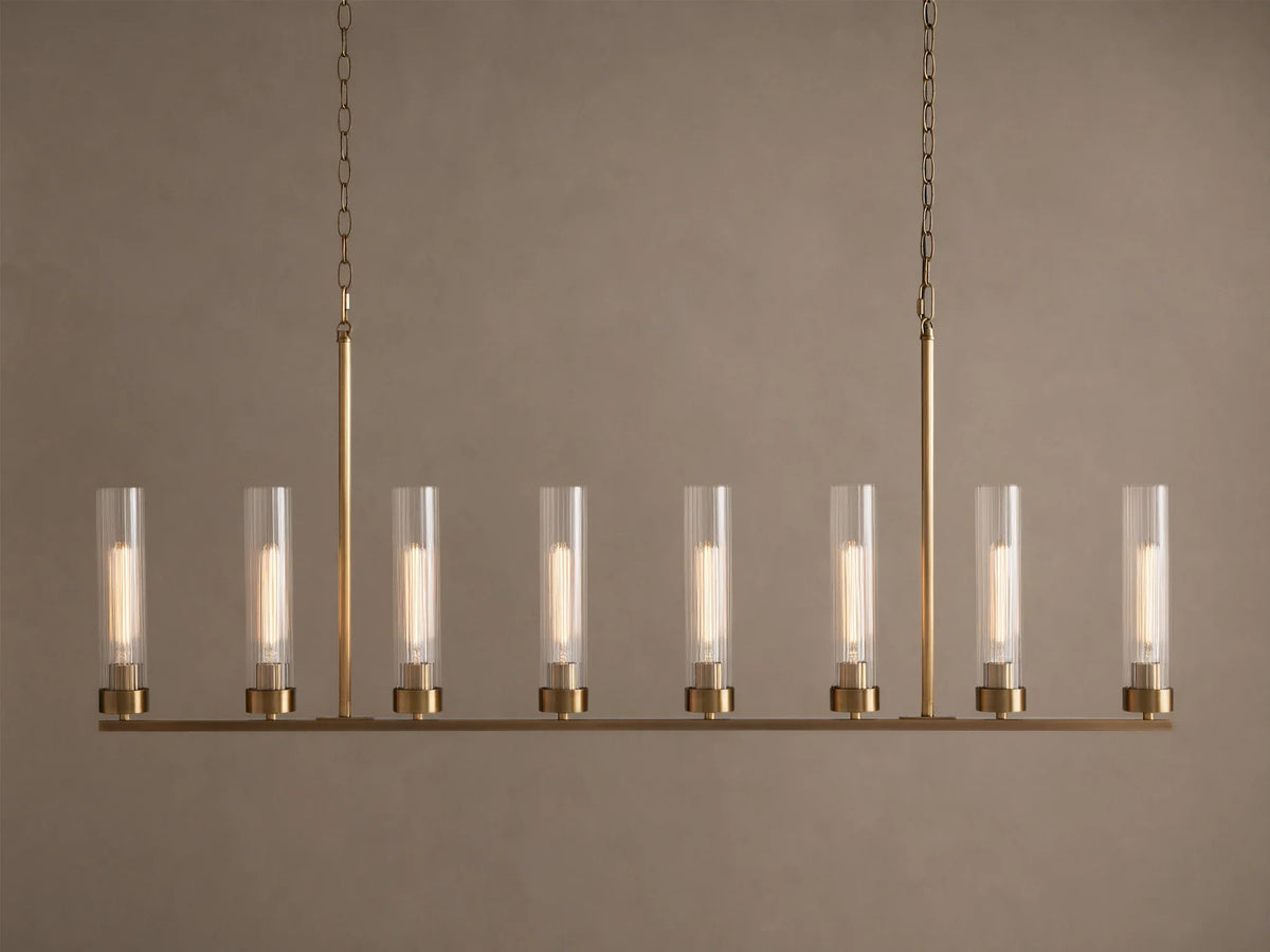 Andreas Linear Chandelier: 8-light, brass-finished, horizontal bar with clear cylindrical glass shades, exposing filament bulbs, hanging.