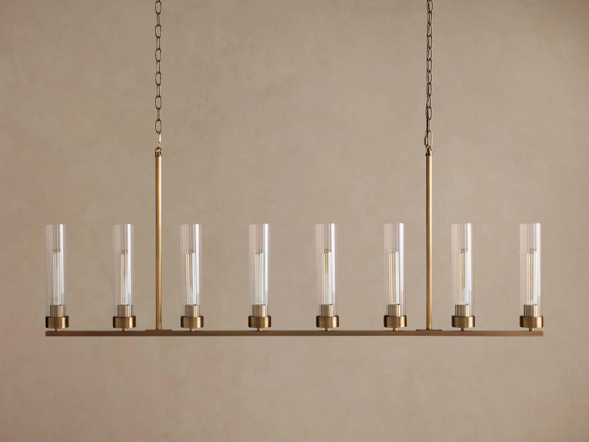 Andreas Linear Chandelier: 8-light, brass-finished, horizontal bar with clear cylindrical glass shades, exposing filament bulbs, hanging.