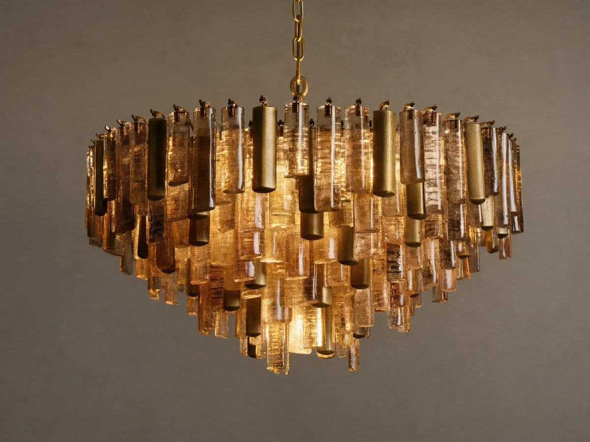 Neve Round Chandelier, illuminated, featuring tiered bronze cast glass and brass rods suspended from a ceiling chain.