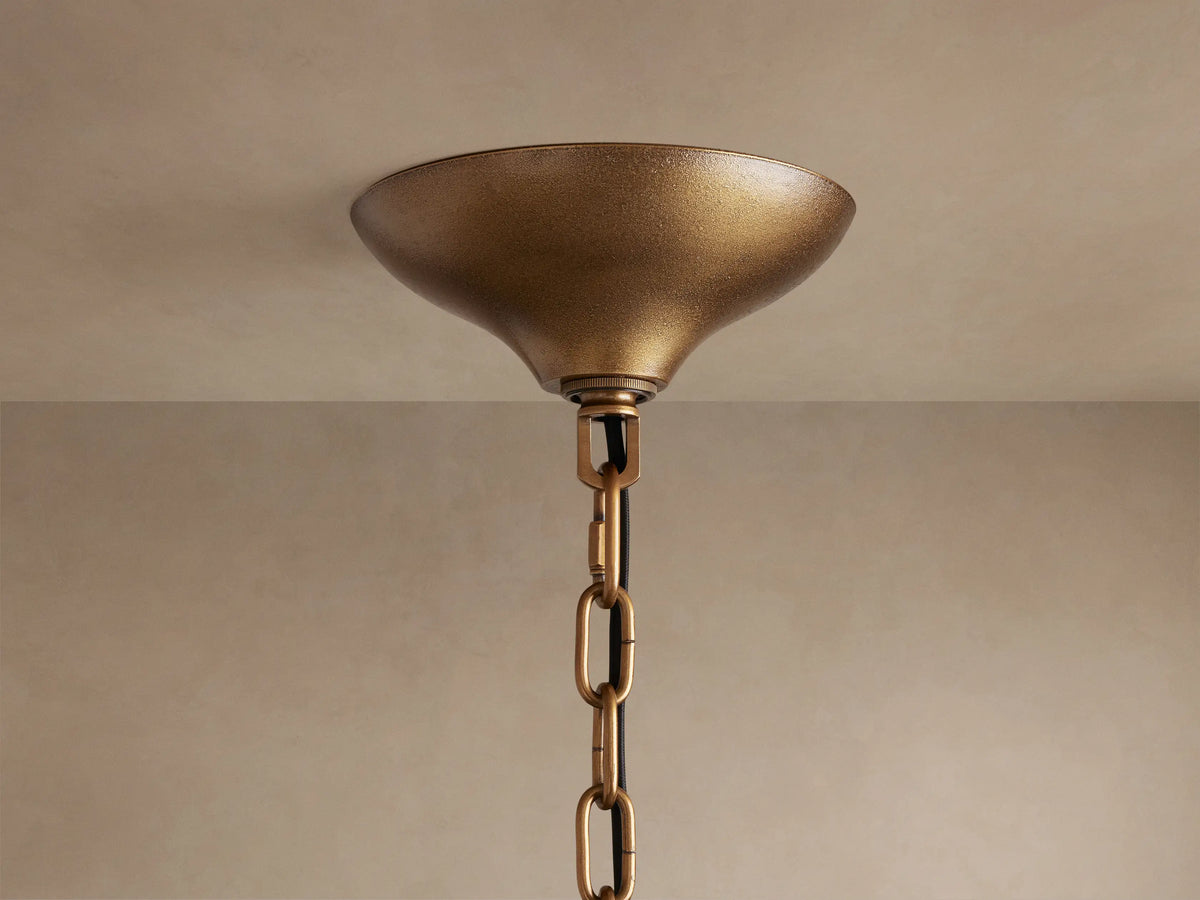 Neve Round Chandelier's textured brass ceiling canopy and chain, mounted on a light beige ceiling.