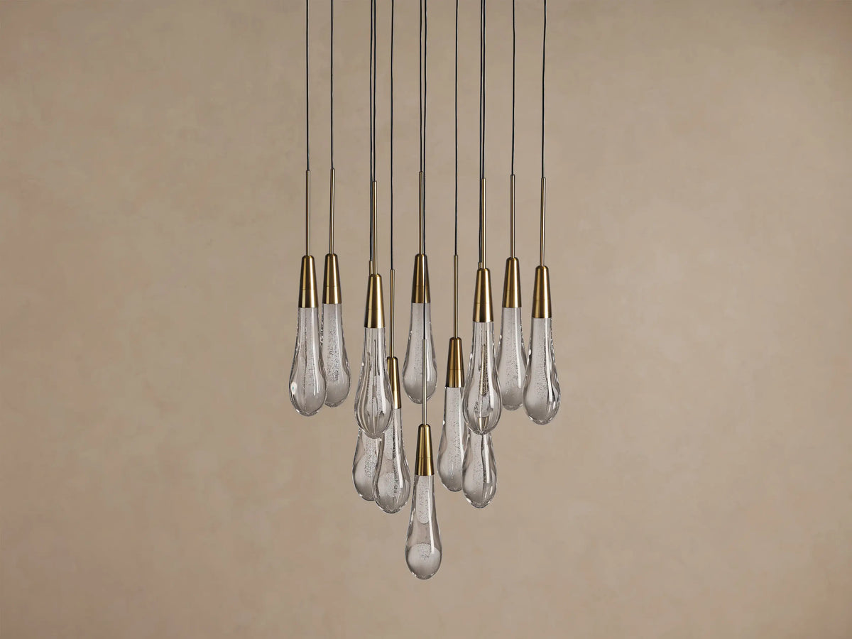 Soltaire Round Chandelier with multiple clear, textured teardrop glass pendants, each with a brass cap, hanging at varying lengths.