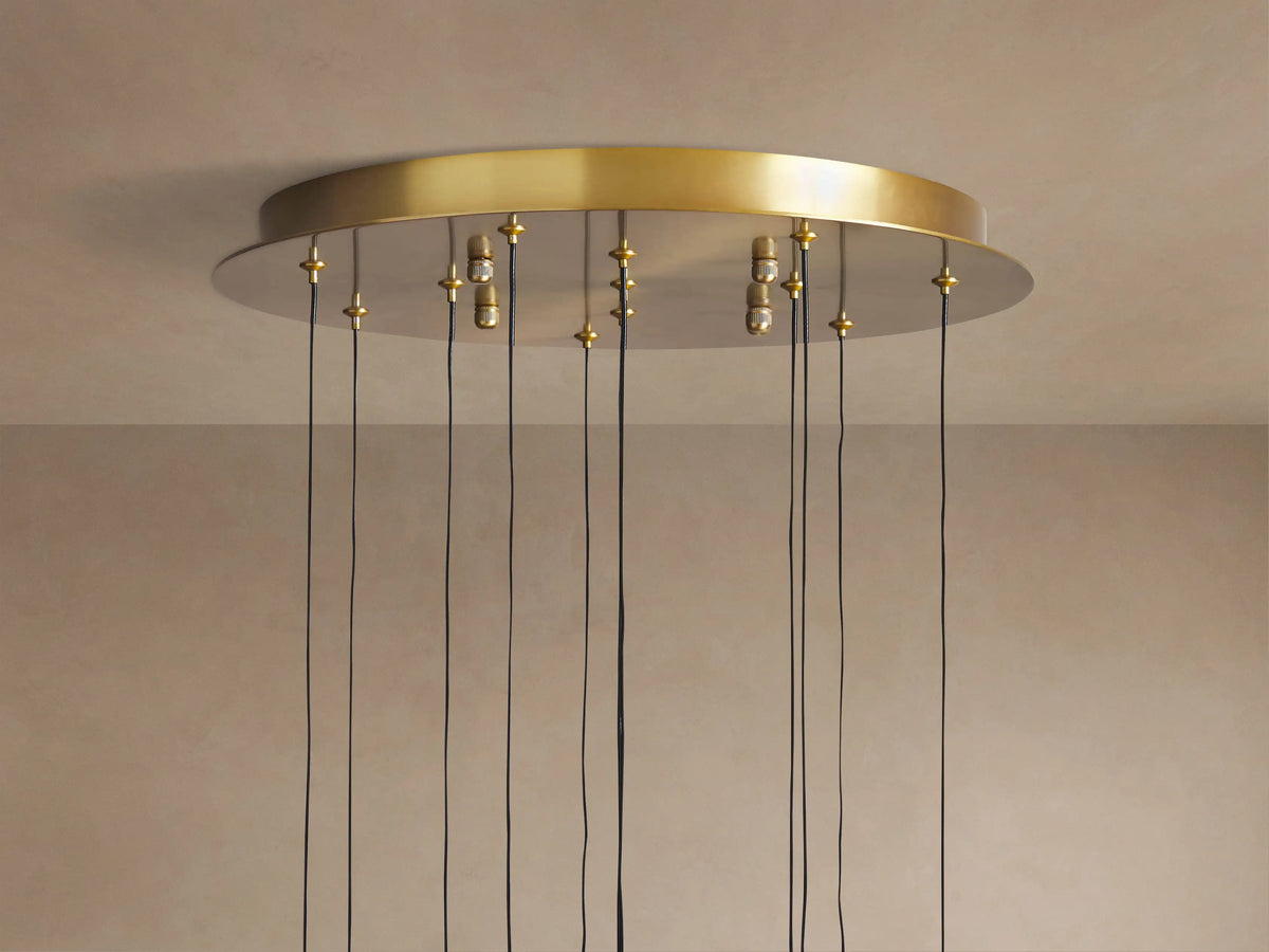 Top of Soltaire Round Chandelier with a brass circular canopy mounted on a light ceiling, many black cords hang down.