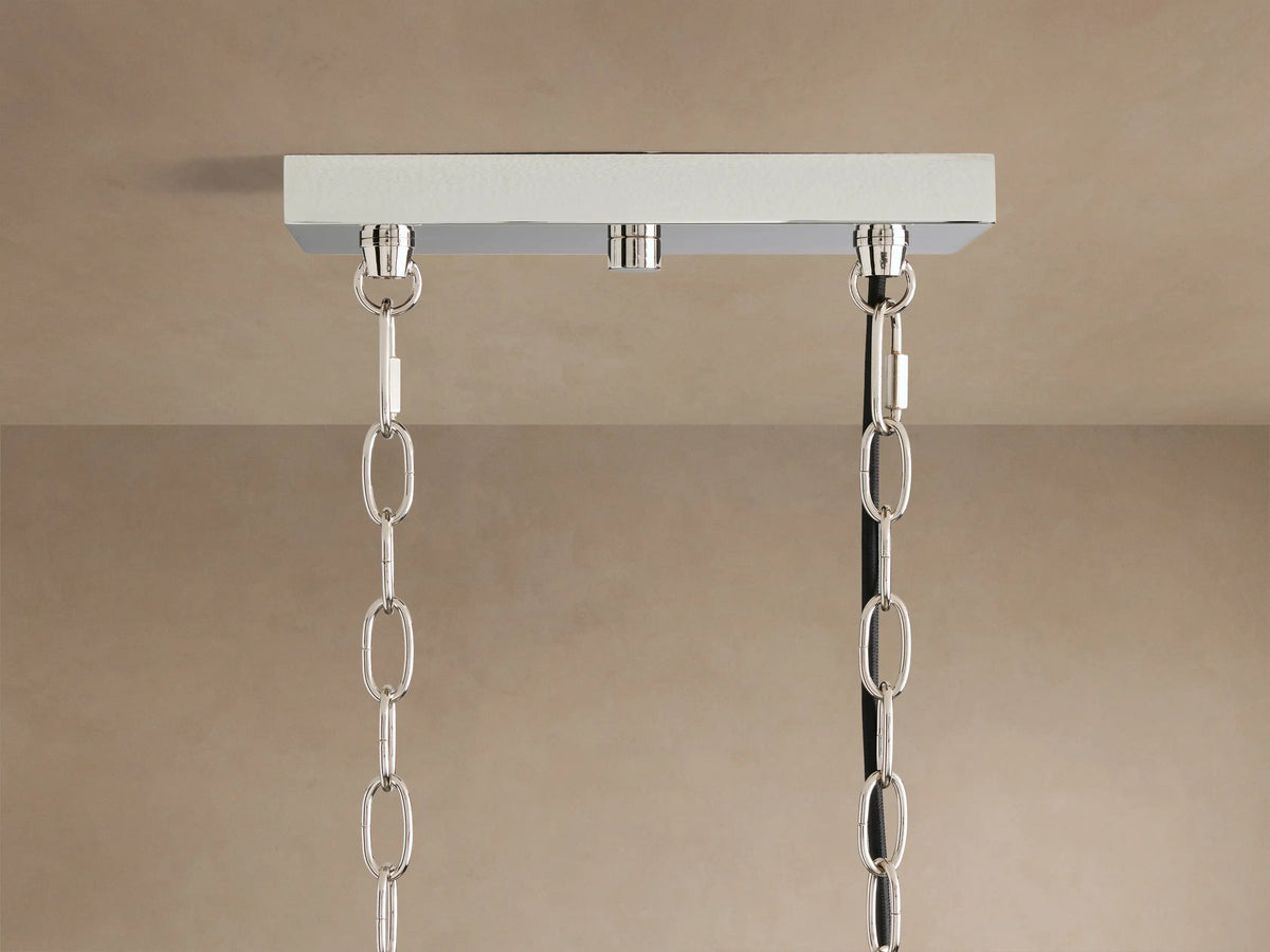 Close-up of Andreas Linear Chandelier: horizontal plated brass bar, five illuminated fluted glass cylinders with warm bulbs.