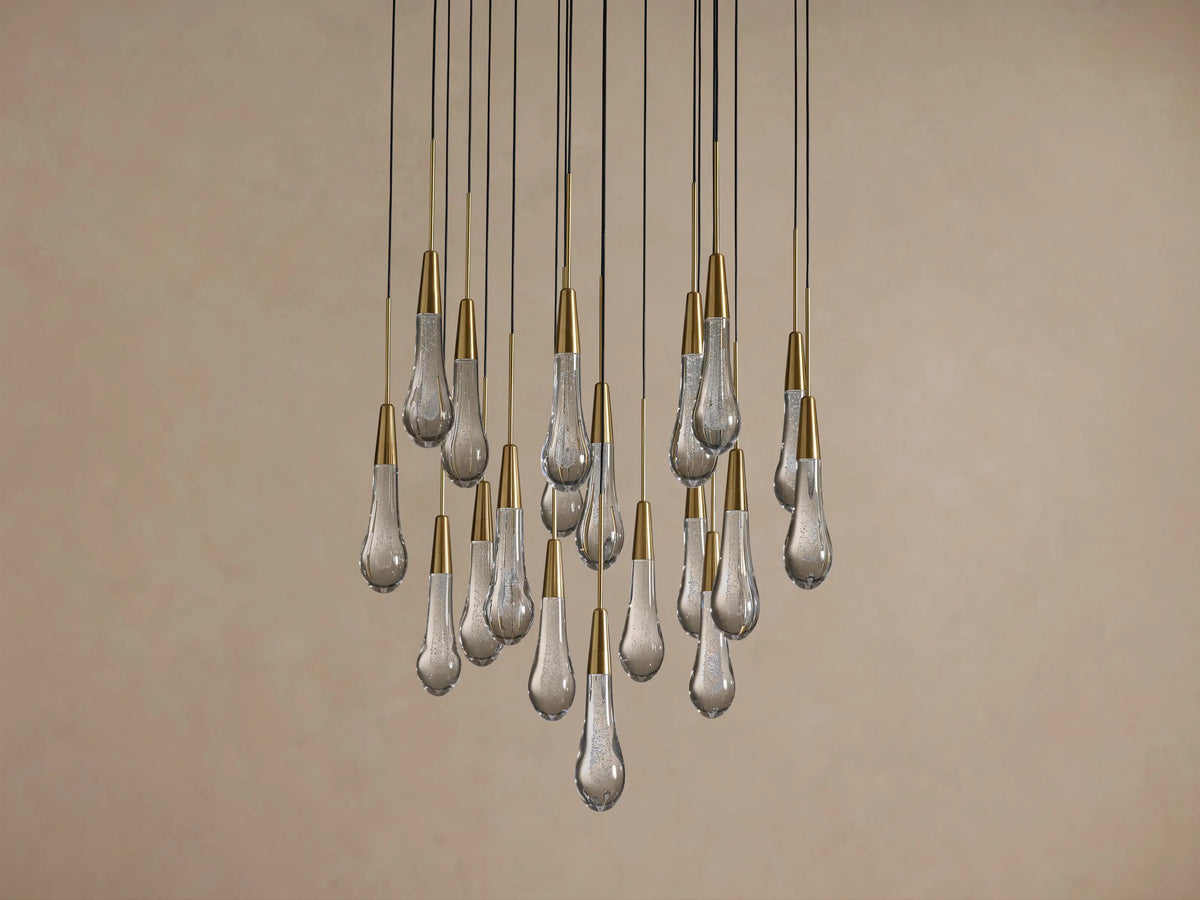 Soltaire Round Chandelier: Numerous clear glass teardrops, textured with bubbles & topped with brass caps, hanging from black cords.