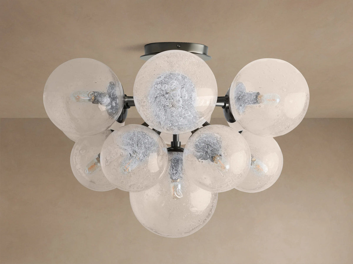 Mandoza Flush Mount with multiple clear, bubbled hand-blown glass globes on a dark metal frame, illuminated.