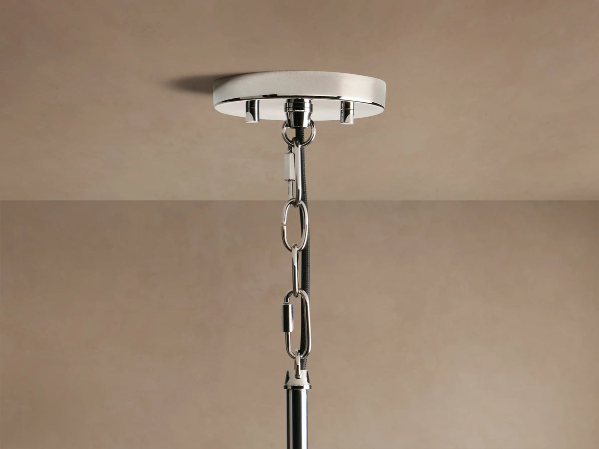Close-up of Andreas Pendant, a cylindrical light with clear ribbed glass shade, polished nickel, and warm filament bulb.