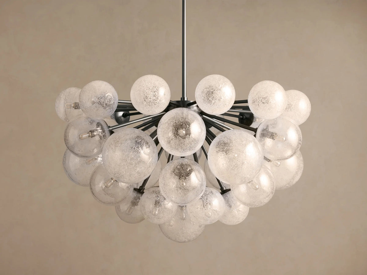 Mandoza Chandelier: Cluster of textured clear glass globes radiating from dark metallic arms, hanging against a light wall.