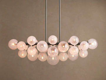 Mandoza Linear Chandelier with a burnished brass frame holding multiple illuminated, speckled hand-blown glass globes.