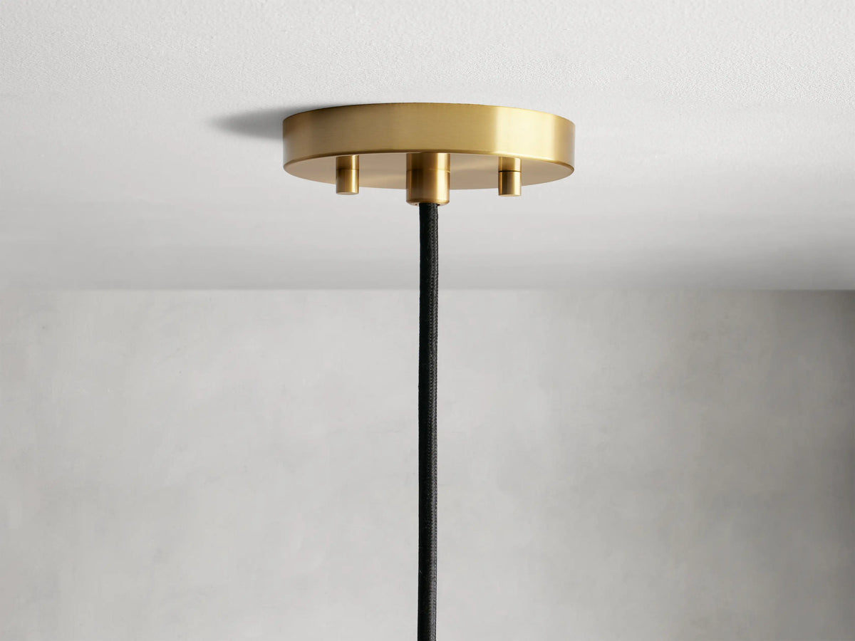 Organic 8" Pendant with a smooth amber-colored mouth-blown glass shade, featuring visible bubbles and brass fittings on a light grey background.