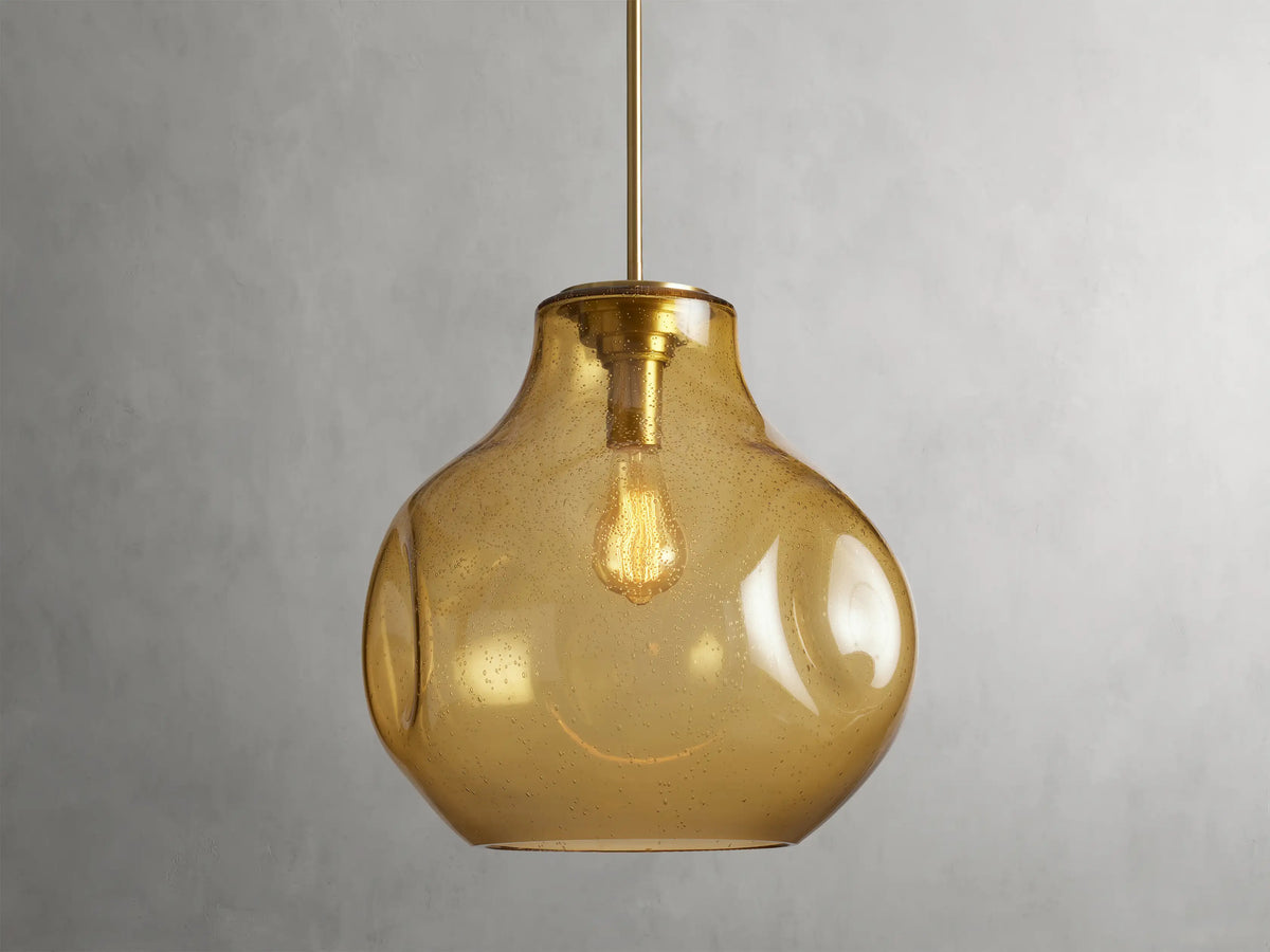 Organic 16" Pendant with amber mouth-blown glass shade, spherical shape, visible bulb inside, hanging by a rod.